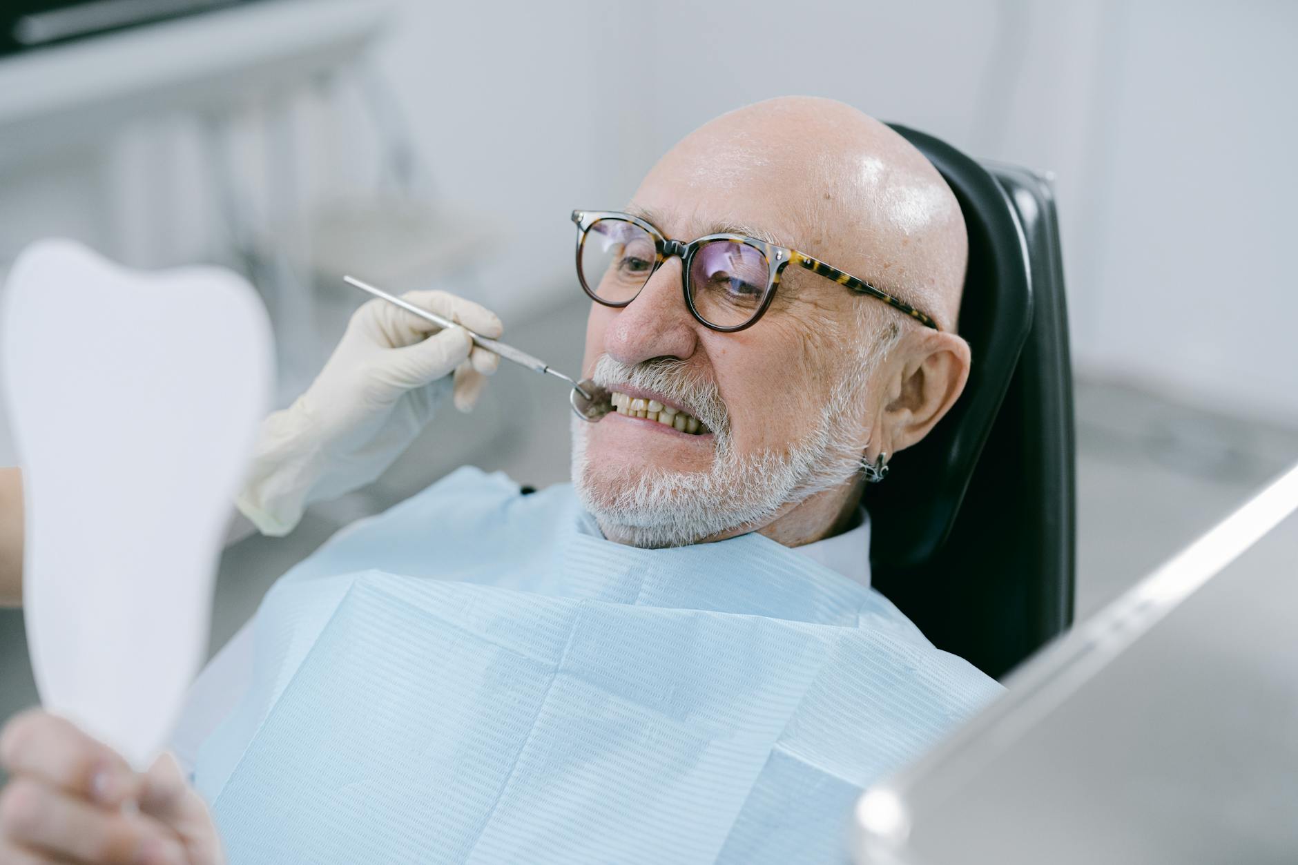 man wearing eyeglasses sitting on dental chair