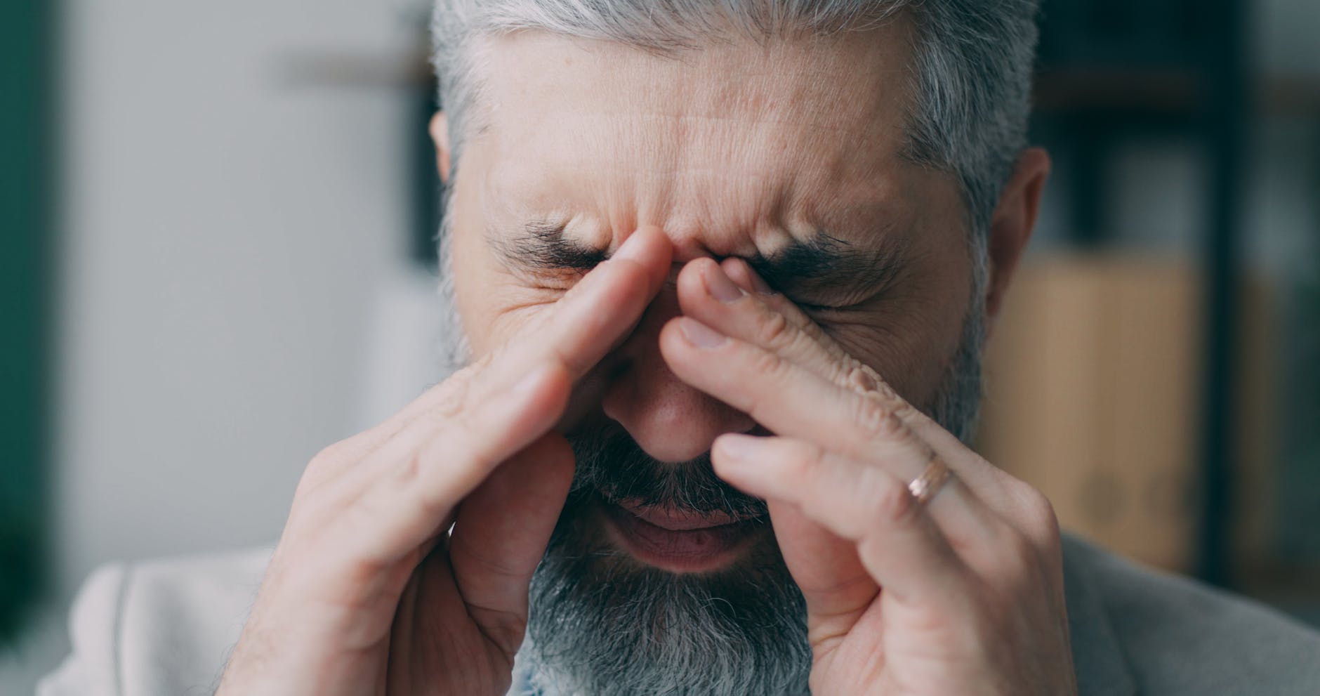 stressed senior man rubbing eyes indoors