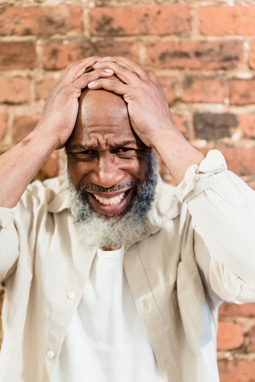 bald man hands on his head