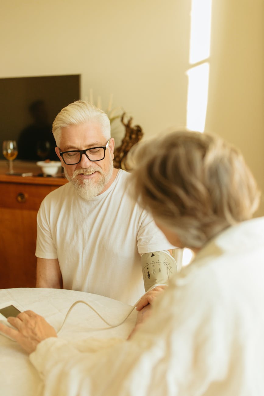 gray haired person checking the man s blood pressure