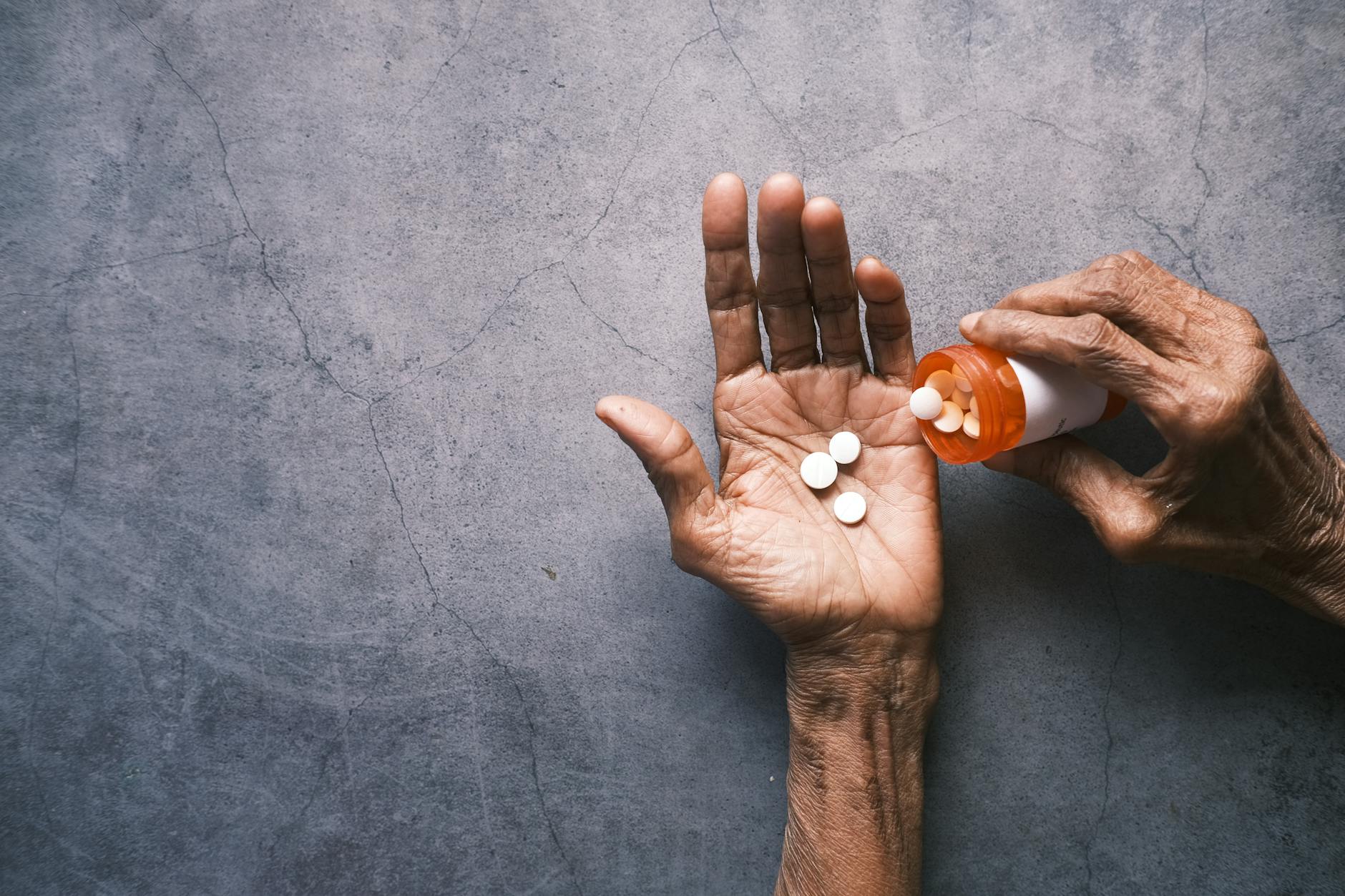 elderly person holding a bottle of tablets