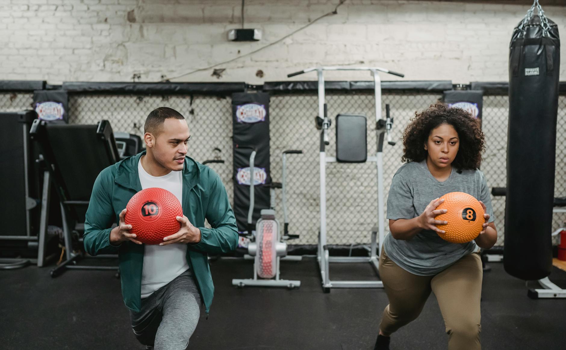 young obese ethnic woman training in gym with personal coach