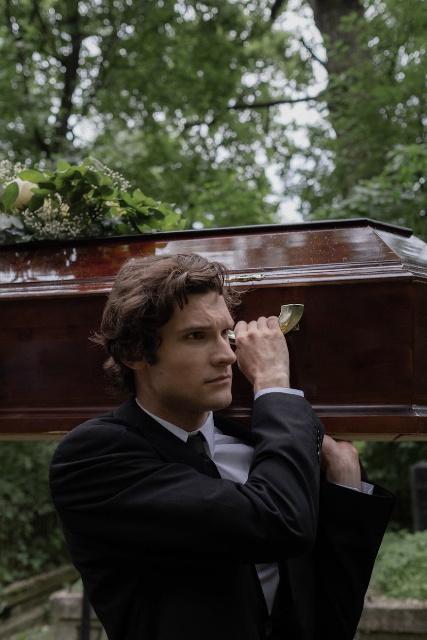 man in black clothes carrying a coffin