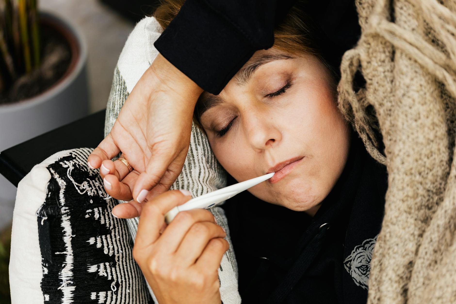 a woman taking her temperature with a thermometer