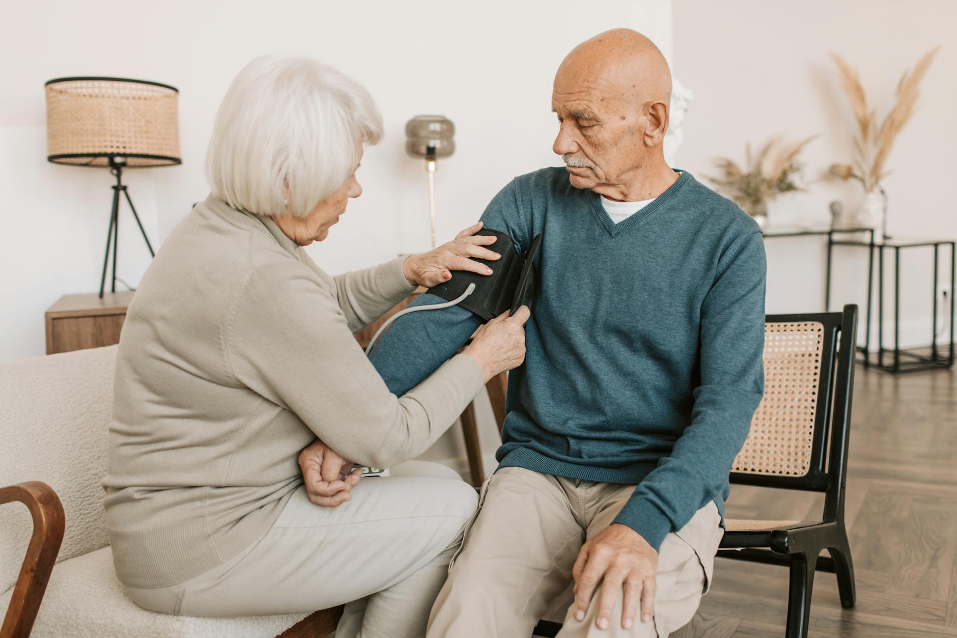 elderly woman checking the blood pressure of an elderly man