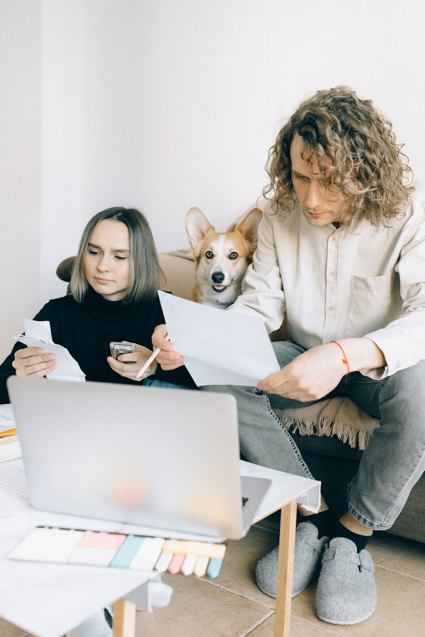 a man and woman sitting on the couch with their dog