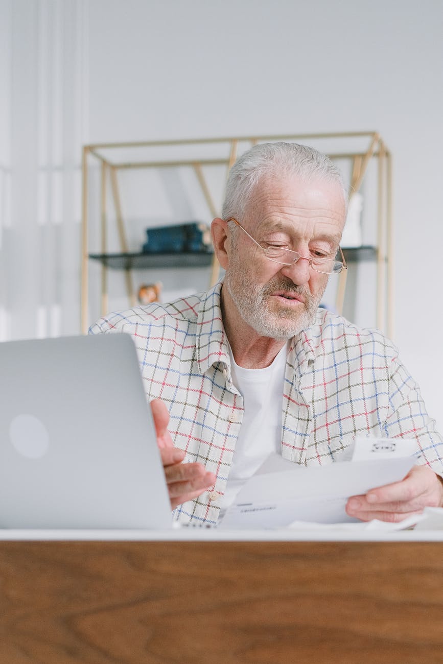 an elderly man wearing eyeglasses while holding documents