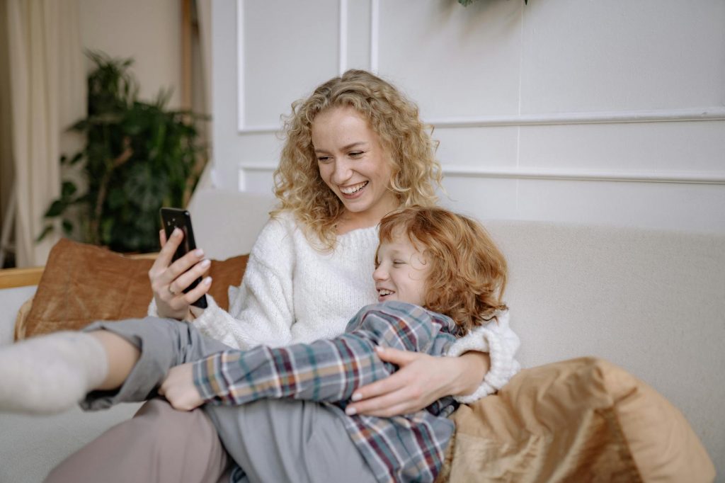 a woman taking a selfie on a couch with her son