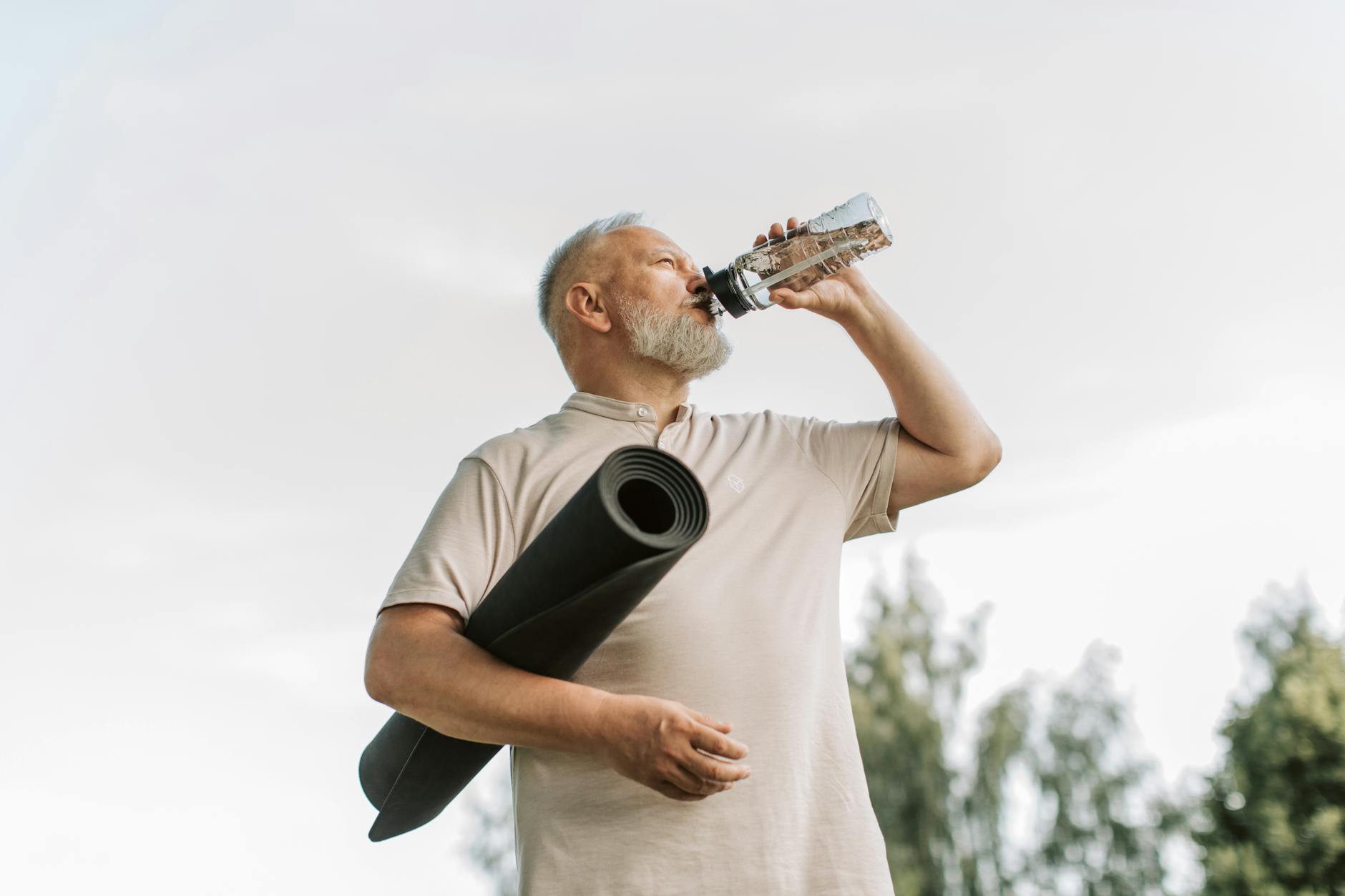 an elderly man sipping water from tumbler