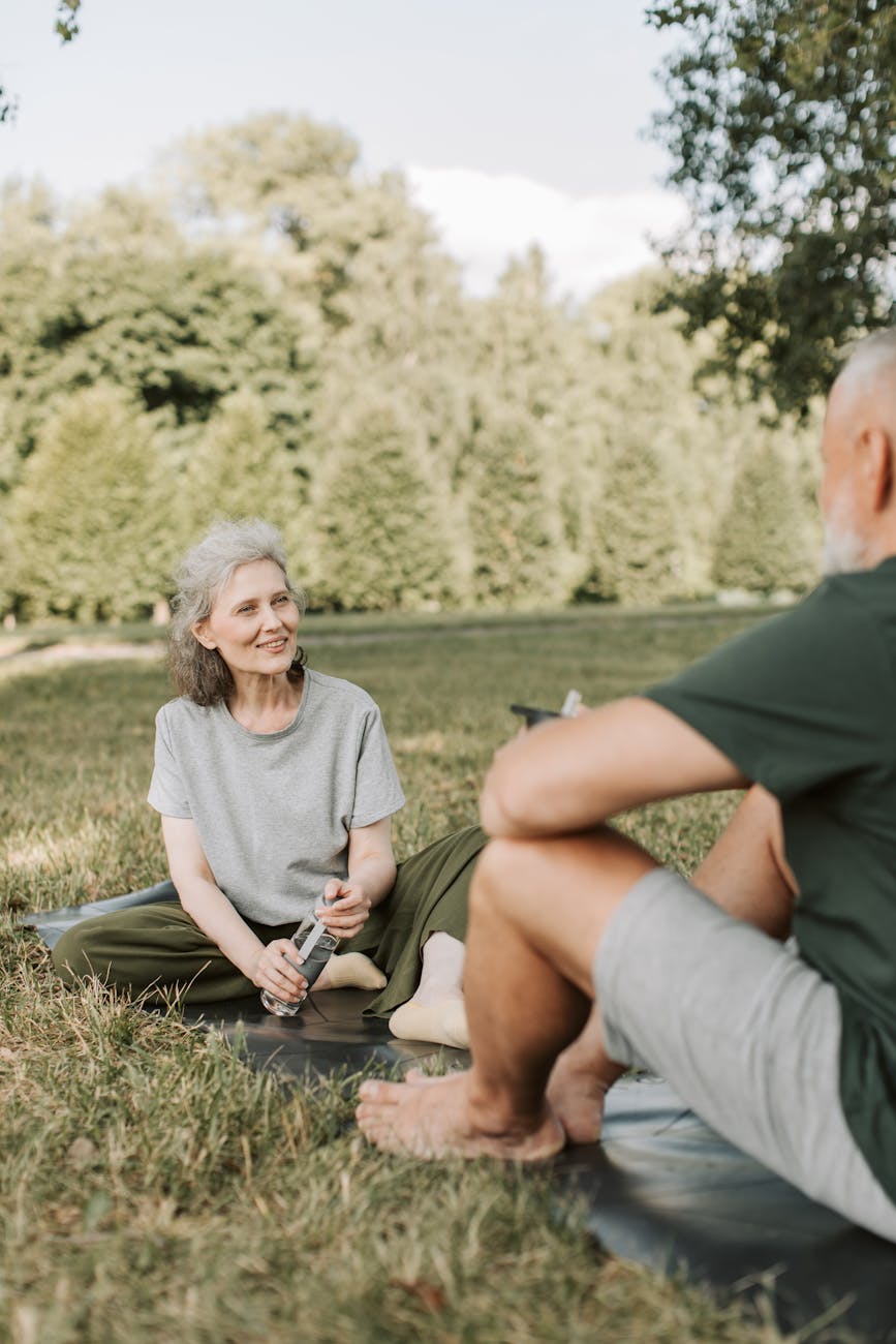 an elderly woman smiling while sitting on yoga mat